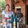 A young woman dressed in traditional Mexican attire smiles while standing next to a selection of tequilas